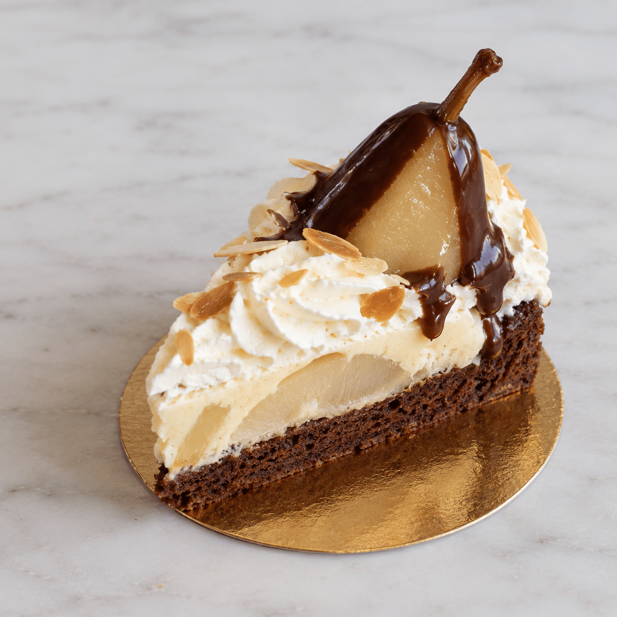 Ein Stück Schokoladenkuchen, garniert mit Schlagsahne, Mandelscheiben und einer pochierten Birnenhälfte, übergossen mit Schokoladensoße, auf einem goldenen Untergrund.